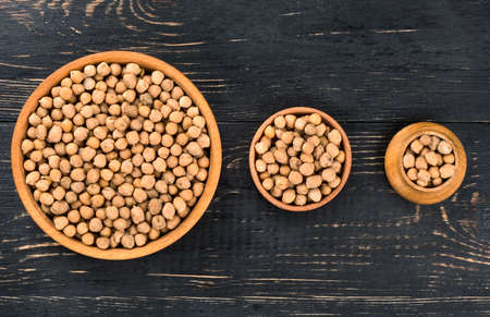 Three bowls of different sizes filled with dry chickpeas on a wooden backgroundの写真素材
