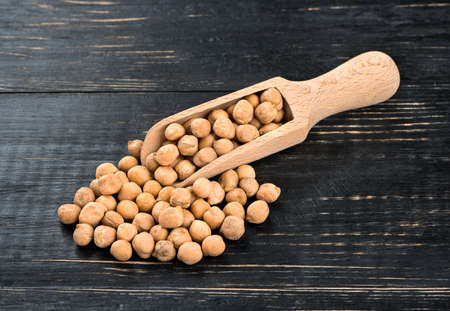 Scatter dried chickpeas in a scoop on a wooden backgroundの写真素材