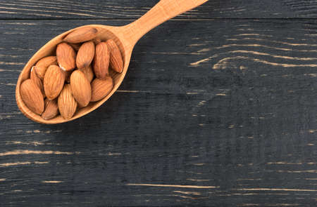 Spoon full of almond nuts on an empty wooden background, top viewの写真素材