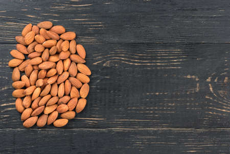 Pile of dry almonds on a blank wooden background, top viewの写真素材