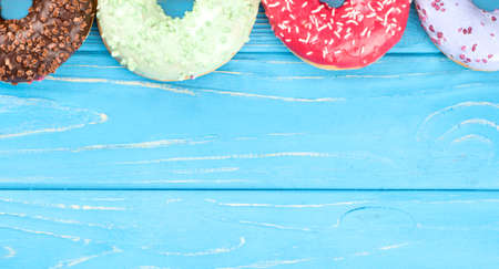Part four donut with multicolored glaze on a blank blue wooden backgroundの写真素材