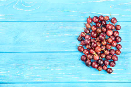 Small handful of red gooseberries on a blank wooden background, top viewの写真素材