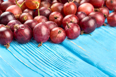 Scattered red gooseberries close-up on a wooden tableの写真素材