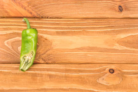 Half of green chili on a blank wooden background, top viewの写真素材