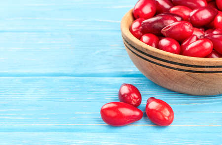 Bowl with cornel berries scattered on the table, close-up