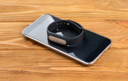 Fitness bracelet with a smartphone on a wooden backgroundの写真素材