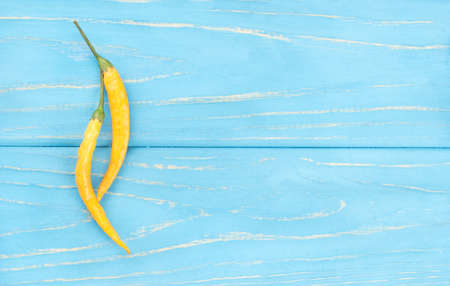 Two hot yellow pepper on an empty wooden background, top view
