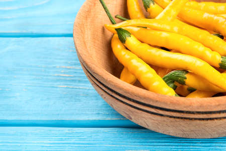 Fresh yellow hot peppers in bowl on a table close-up