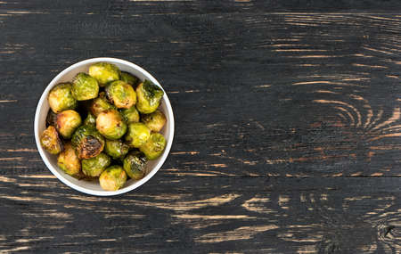 Bowl with fried Brussels sprouts on a blank wooden backgroundの写真素材