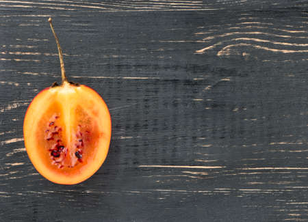 Fresh fruit tamarillo half a blank on a wooden background, top view