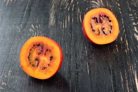 Two halves of fresh fruit tamarillo on a dark table closeupの写真素材