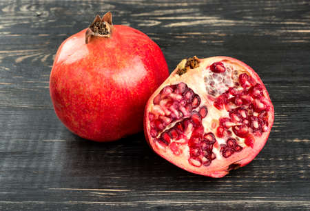 Fresh fruit with a juicy pomegranate half on a wooden backgroundの写真素材