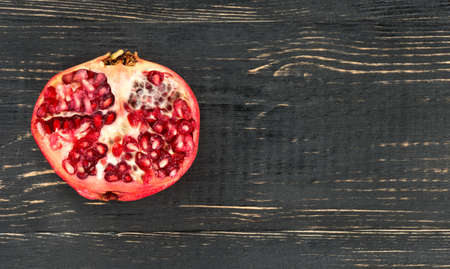 Juicy half of pomegranate on a blank wooden backgroundの写真素材