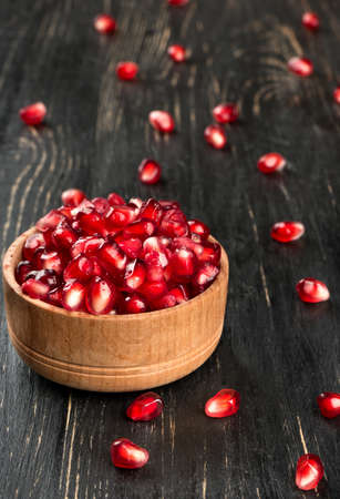 Fresh pomegranate seeds in a bowl and scattered on the tableの写真素材