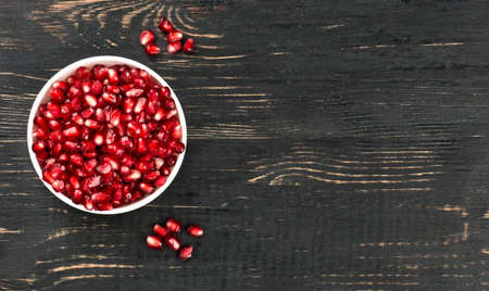 White bowl filled with pomegranate seeds on an empty table, top viewの写真素材