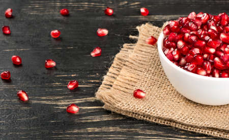 Part of the bowl with pomegranate seeds on sackcloth and tableの写真素材