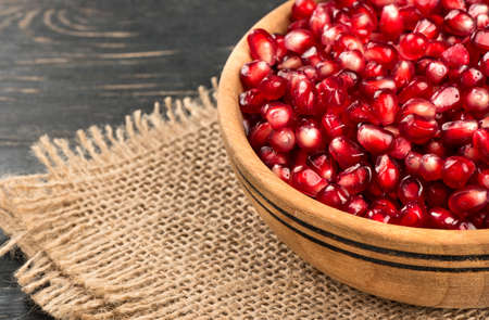 Part bowl filled with pomegranate seeds on sacking close-upの写真素材