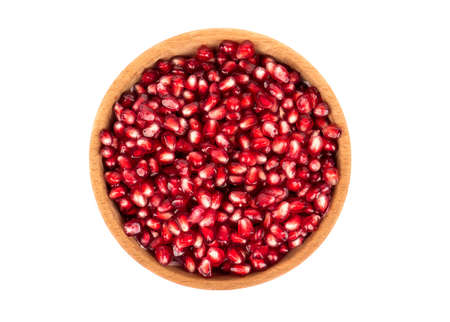 Pomegranate seeds in a wooden bowl isolated on white background top viewの写真素材