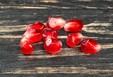 Ripe pomegranate seeds scattered on a wooden background close upの写真素材