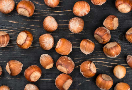 Scattered raw hazelnuts in shell on a wooden background, top viewの写真素材