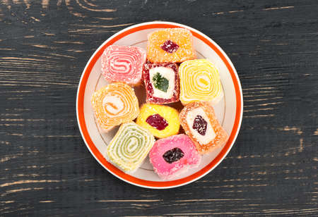 Plate with various pieces of turkish delight lokum on a wooden background, top viewの写真素材