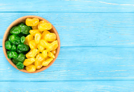 Bowl with green and yellow dried kumquat on a blank wooden background, top view