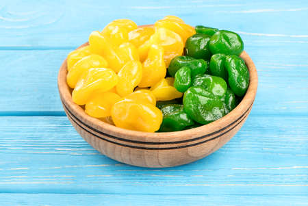 Bowl of dried yellow and green kumquat on blue tableの写真素材