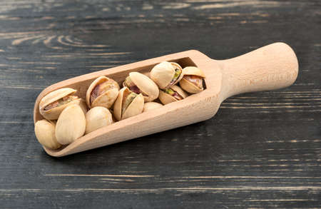 Pistachio nuts in a scoop on a wooden backgroundの写真素材