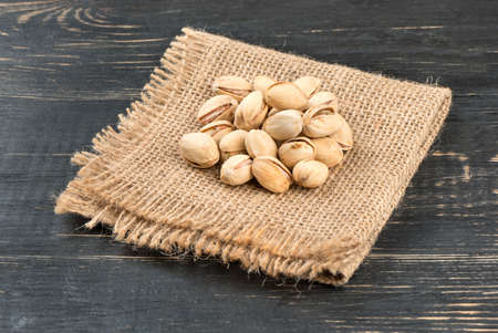 Salted pistachio nuts on burlap and tableの写真素材