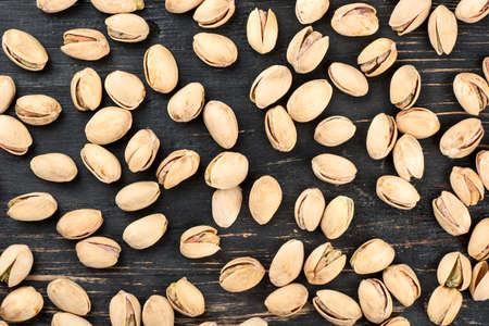 Scattered pistachio nuts on a wooden background, top viewの写真素材