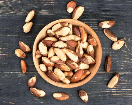 Bowl filled with Brazilian nuts on a wooden background, top viewの写真素材