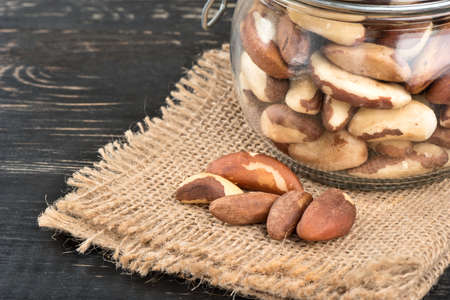 Brazil nuts in a jar on burlap and dark tableの写真素材