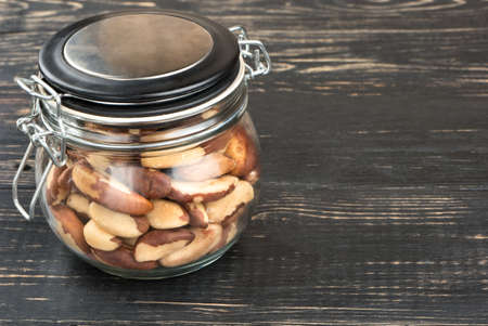 Jar filled with Brazilian walnut on an empty wooden backgroundの写真素材