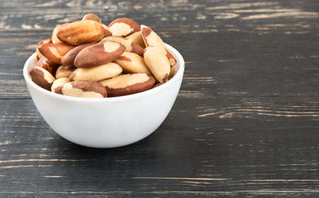 White bowl filled with Brazilian nuts on a wooden backgroundの写真素材