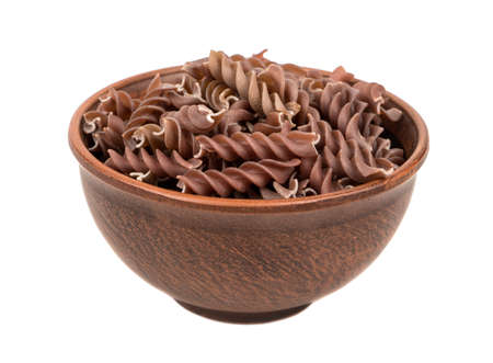 Uncooked pasta fussili in a large bowl on white backgroundの写真素材