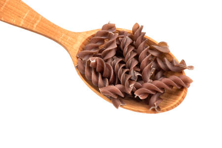 Dark raw fusilli pasta in spoon on white background, closeupの写真素材