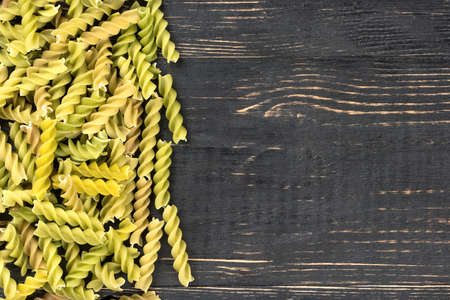 Scattered green pasta fusilli on an empty wooden backgroundの写真素材