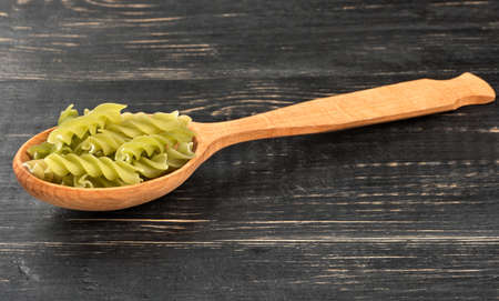 Green fusilli pasta in spoon on wooden backgroundの写真素材