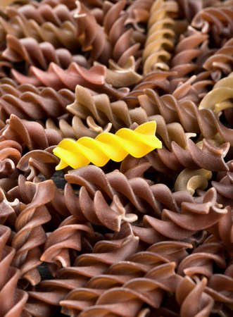 Scattered dark raw pasta fusilli with a yellow close-upの写真素材
