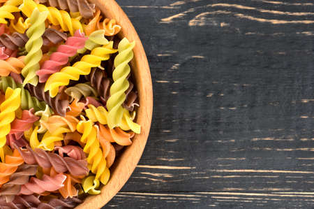 Part of the bowls with multi-colored fusilli pasta on the table, top viewの写真素材
