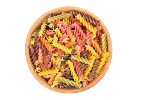 Colored pasta fusilli in a wooden bowl on white background, top viewの写真素材