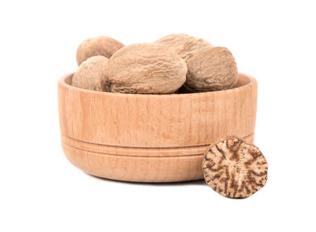 Dry nutmeg in a bowl with half on white background