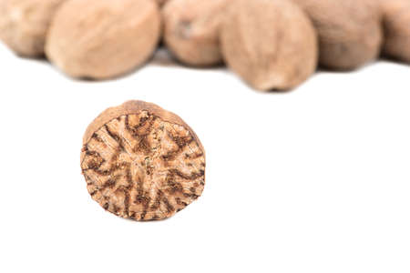 Half nutmeg with scatter nuts on a white background