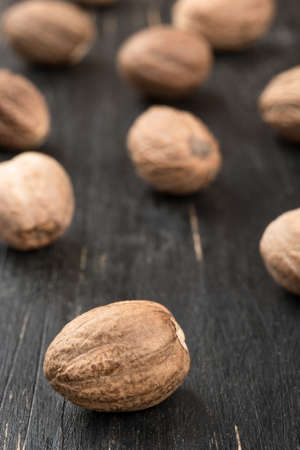 Scattered dry nutmeg on a wooden background closeup