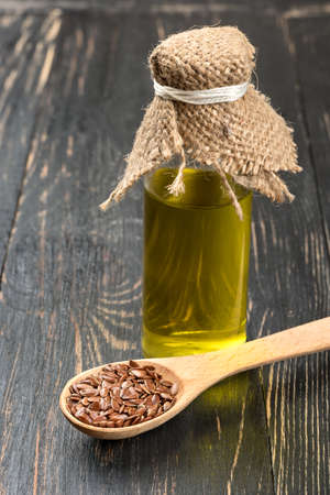 Linseed oil in a bottle with beans in spoon on wooden background close-upの写真素材