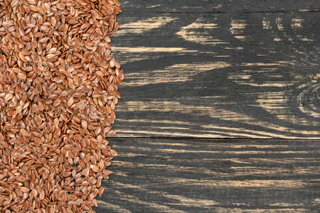 Scattered flax seeds on an empty wooden background, top viewの写真素材