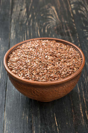 Bowl is filled with flax seeds on wooden backgroundの写真素材