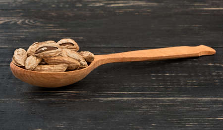 Wild uzbek almonds in a wooden spoon on wooden background