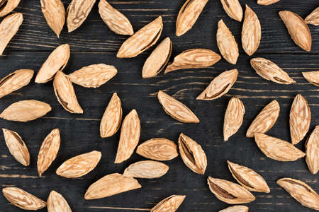 Scattered uzbek inshell almonds on wooden background