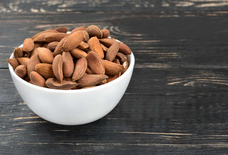 Wild uzbek almonds without the shell in a bowl on wooden backgroundの写真素材